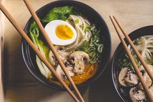 Traditional Japanese Ramen Soup With Mushrooms, Bok Choy, Greens In Two Black Bowls On The Orange Background, Top View, Close Up