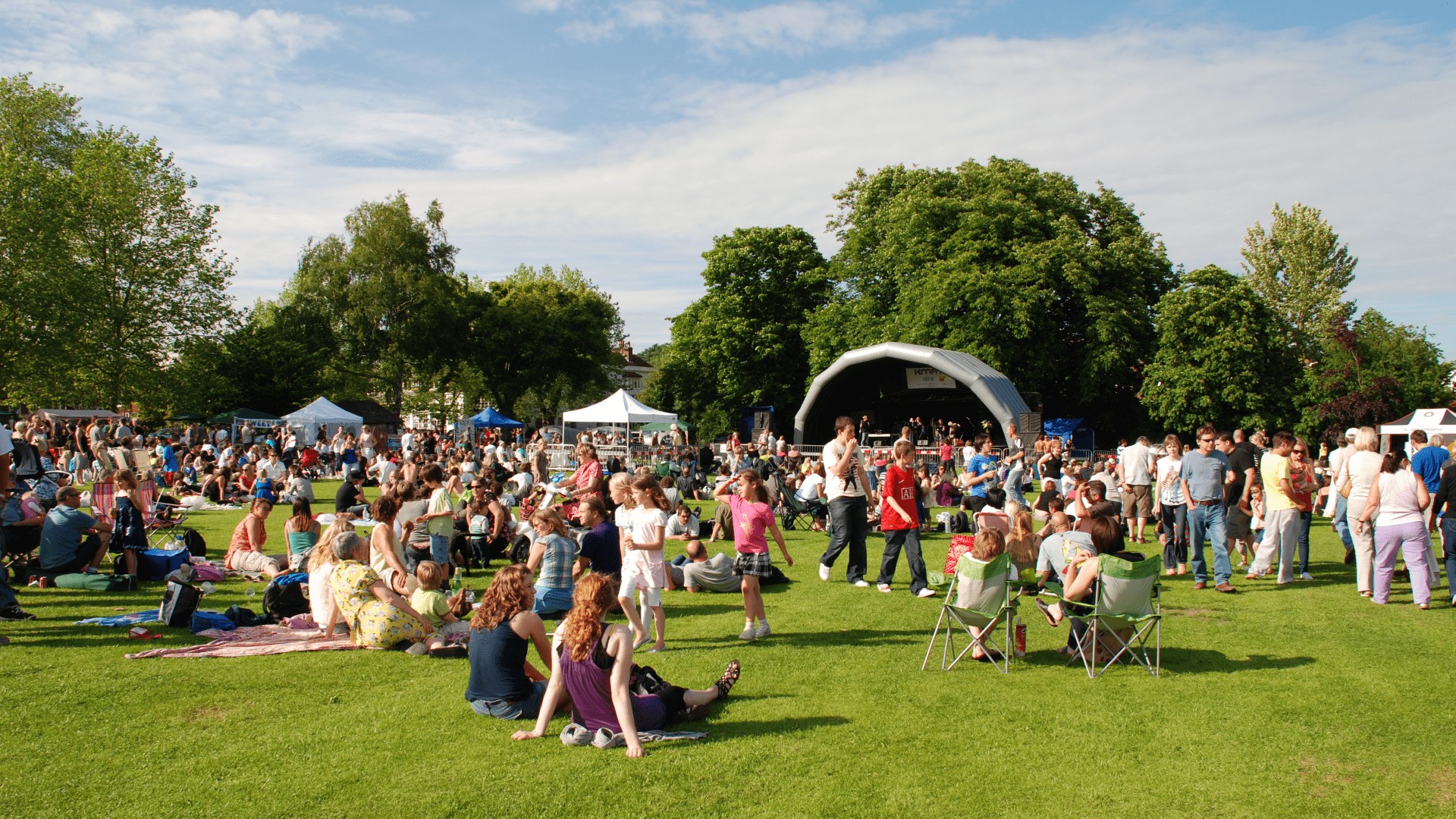 A diverse crowd gathered on the grass at a festival, enjoying the vibrant atmosphere and festivities.